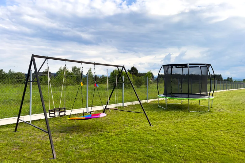 Plac zabaw dla dzieci z huśtawkami i trampoliną przy domkach w Dębnie